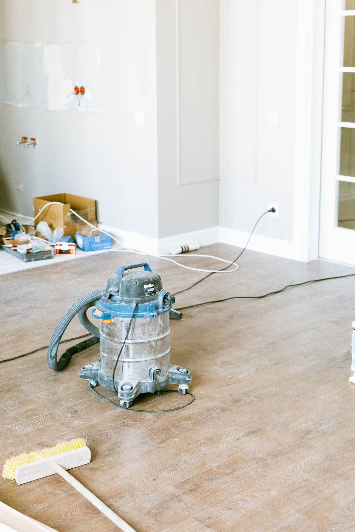 Aspirateur de chantier et balai dans une pièce fraîchement rénovée